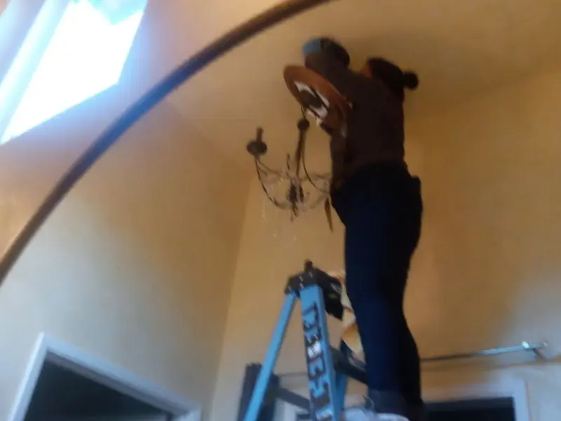 Electrician installing a chandelier in a Nogales residence